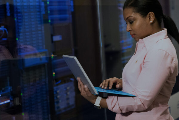 Mulher olhando notebook em frente a um data center