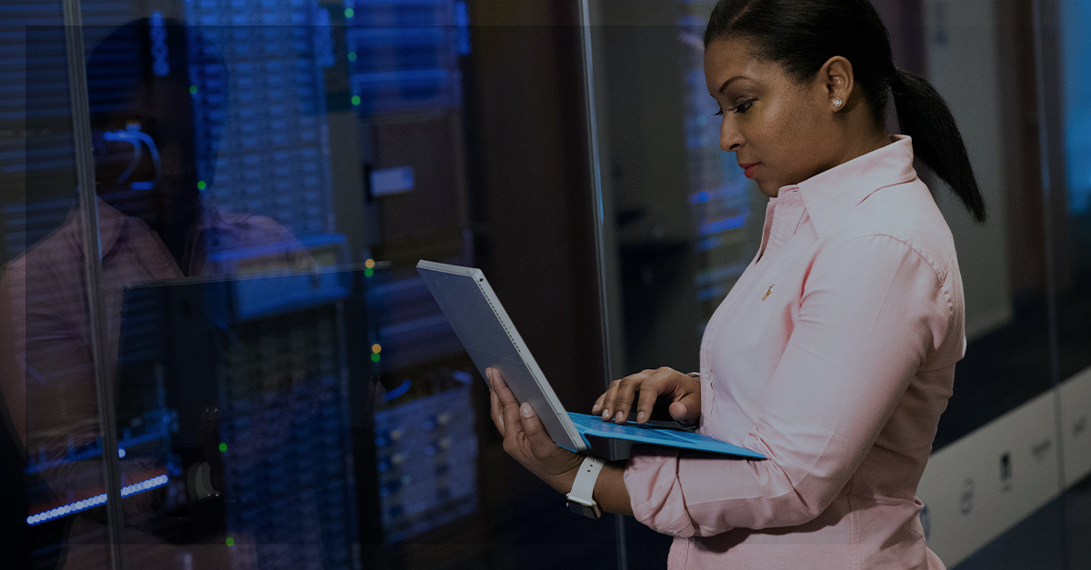 Mulher olhando notebook em frente a um data center