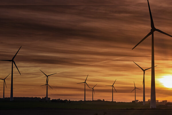 Parque eólico ao pôr do sol, destacando tecnologias sustentáveis para descarbonização e combate às mudanças climáticas.