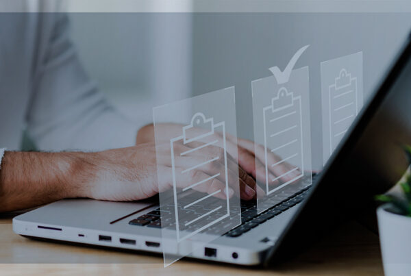 Pessoa digitando em um notebook com ícones transparentes de checklists flutuando à frente da tela, simbolizando digitalização e organização de documentos.