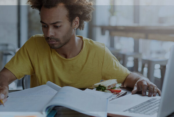 IA no dia a dia: pessoa estudando com caderno aberto e notebook, fazendo anotações para trabalho e estudos.