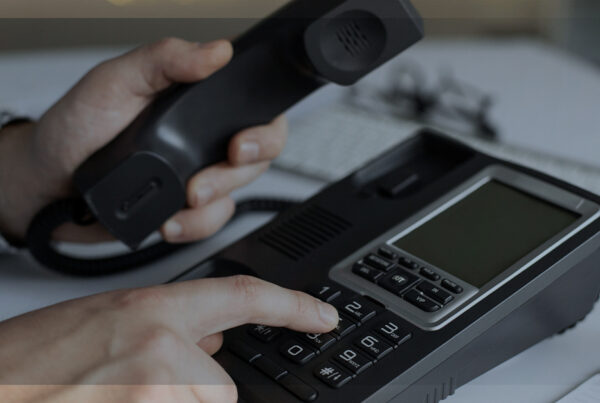 Ramais móveis: mão discando em telefone de mesa, representando mobilidade no atendimento corporativo.